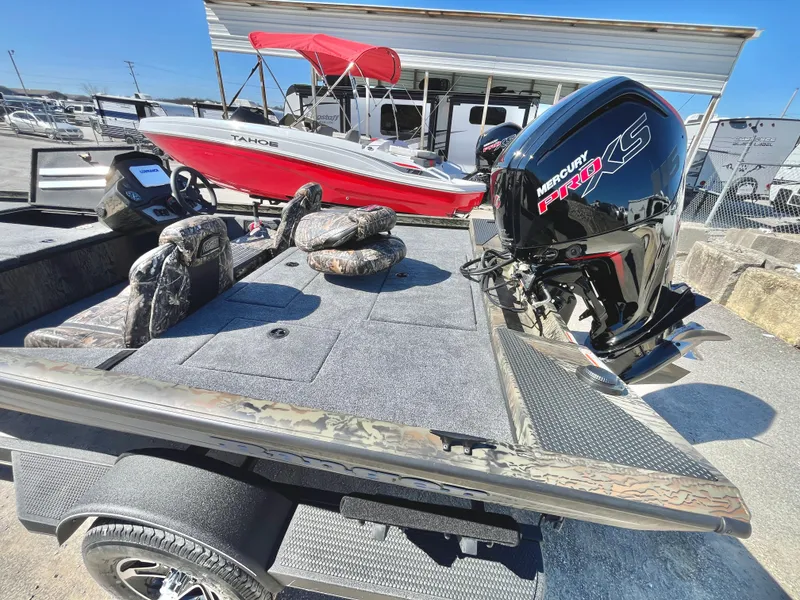 Slide: The Image of 2025 Ranger RT188 boat with Mercury engine, parked outdoors near a red boat. - 13