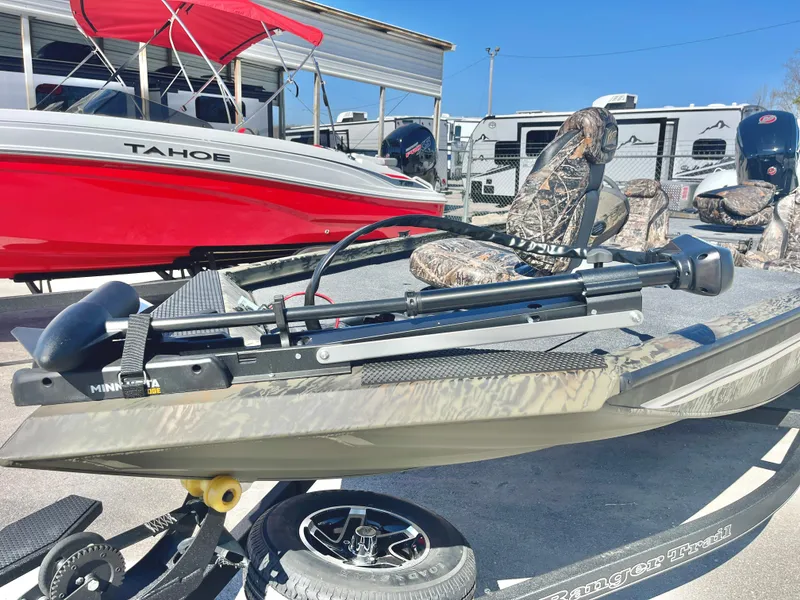 Slide: The Image of 2025 Ranger RT188 boat with camo seats and trolling motor, parked near a red Tahoe boat. - 9