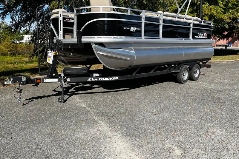 The Image of 2025 Sun Tracker SportFish 20 DLX pontoon boat on trailer, parked outdoors. - 1
