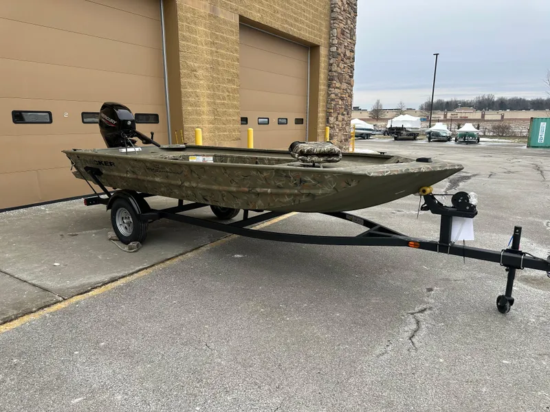 Slide: The Image of 2025 Tracker Grizzly 1654 T Sportsman boat on trailer, parked outside a building. - 25