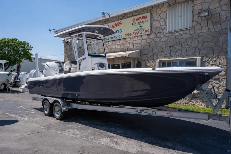 Slide: The Image of 2025 Robalo R246 CAYMAN boat on trailer, parked outside a dealership. - 21