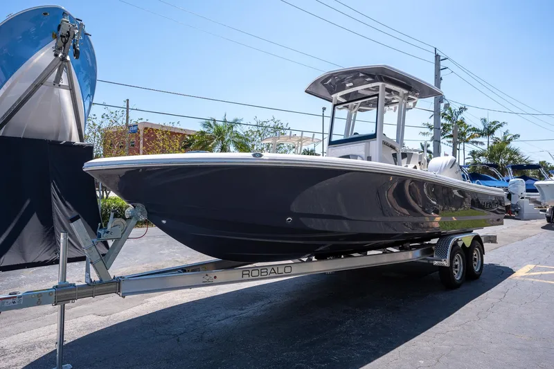 Slide: The Image of 2025 Robalo R246 CAYMAN boat on trailer, parked outdoors under clear sky. - 3