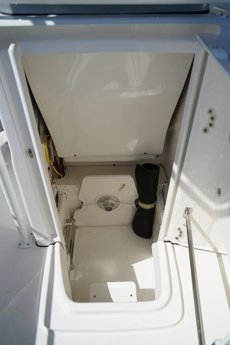 Slide: The Image of 2025 Robalo R200 boat storage compartment with white interior and black mat. - 11