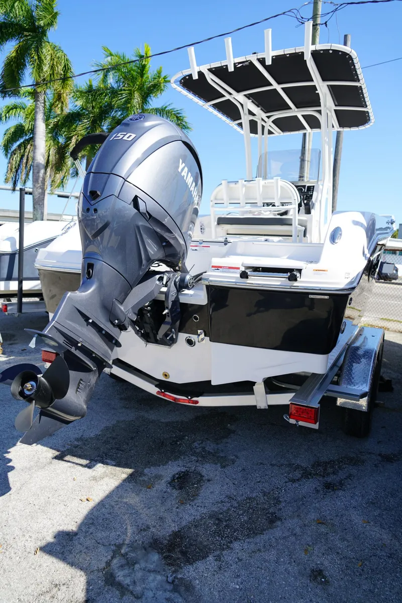 Slide: The Image of 2025 Robalo R200 boat with Yamaha engine, parked on a trailer under palm trees. - 21
