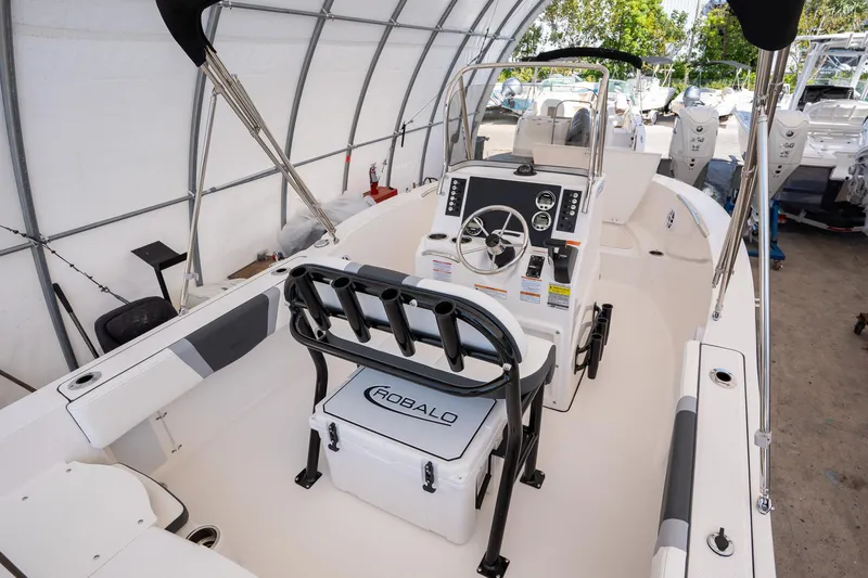 Slide: The Image of 2025 Robalo R180 boat interior with steering console and seating in a covered storage area. - 11