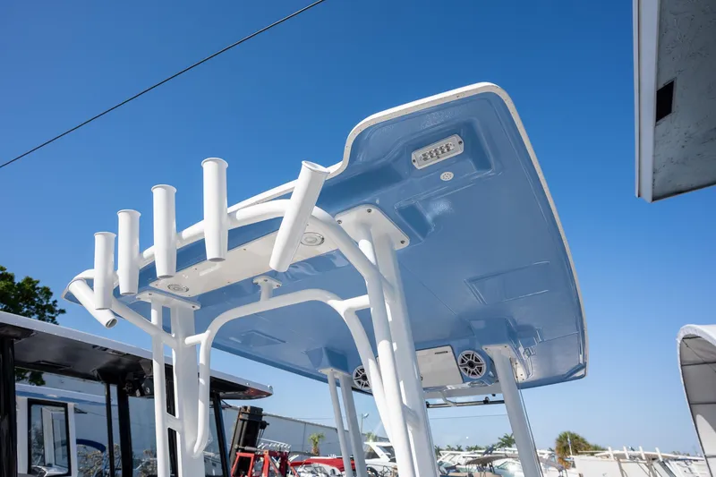 Slide: The Image of 2025 Robalo R270 boat T-top with rod holders and speakers under clear blue sky. - 11