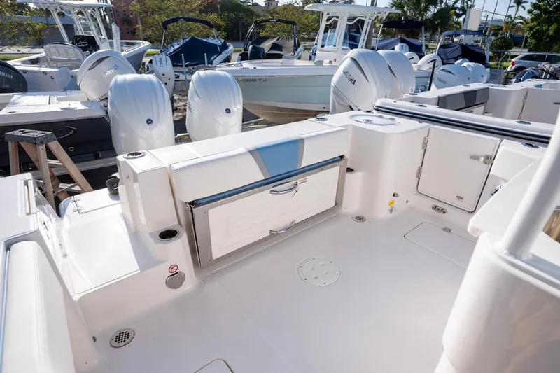 Slide: The Image of 2025 Robalo R270 boat interior with storage compartments and seating, docked among other boats. - 16