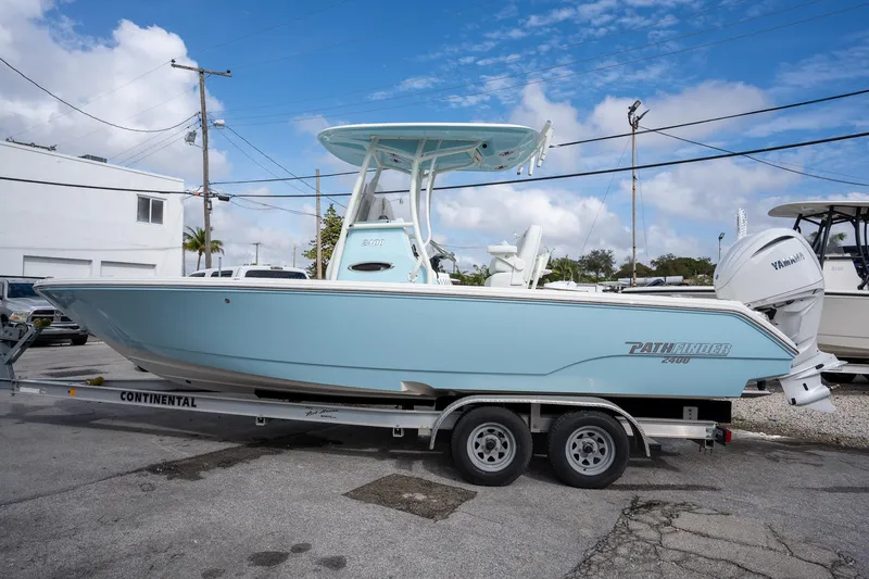 Slide: The Image of 2025 Pathfinder 2400 TRS boat on trailer, light blue, parked outdoors. - 1