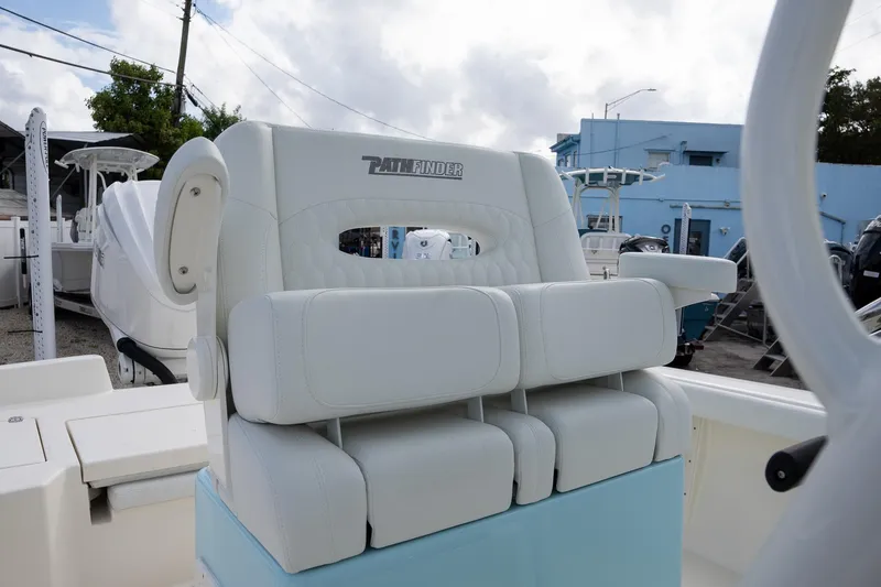 Slide: The Image of 2025 Pathfinder 2400 TRS boat seat with white upholstery and armrests, docked outdoors. - 11