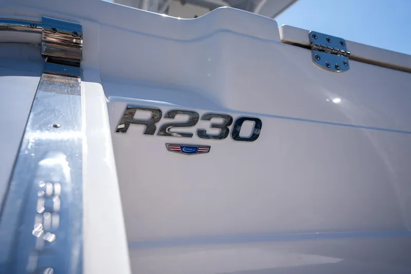 Slide: The Image of 2025 Robalo R230 boat emblem on white hull, close-up view. - 8