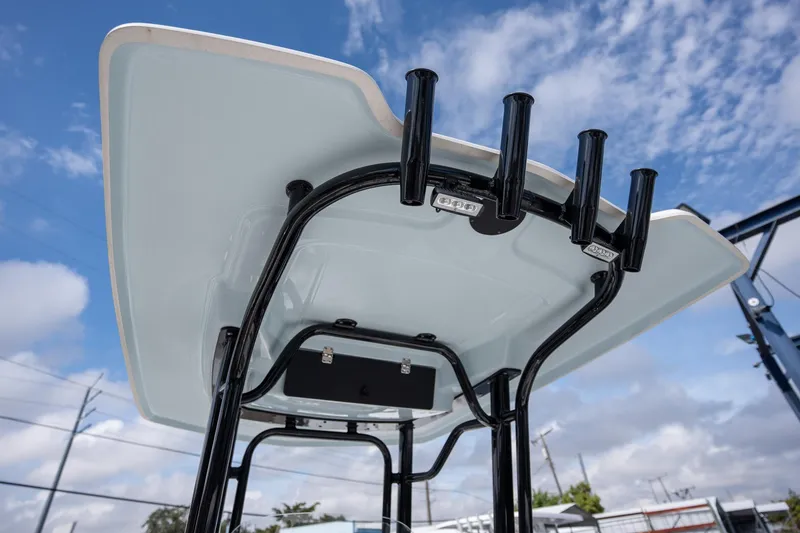 Slide: The Image of 2025 Robalo R230 boat T-top with rod holders against a blue sky. - 10