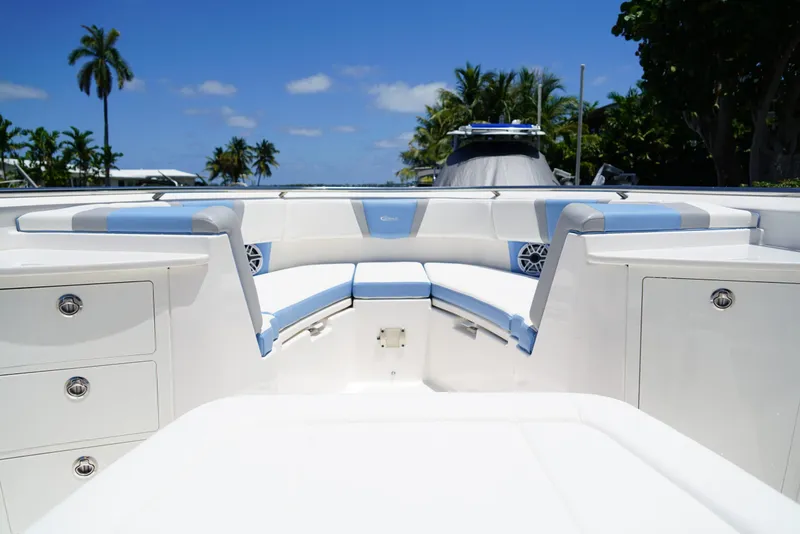 Slide: The Image of 2024 Robalo R360 boat interior with white and blue seating, palm trees in background. - 14