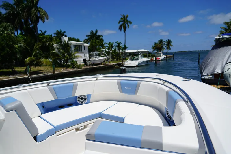 Slide: The Image of 2024 Robalo R360 boat with luxurious seating, docked by a scenic waterfront. - 15