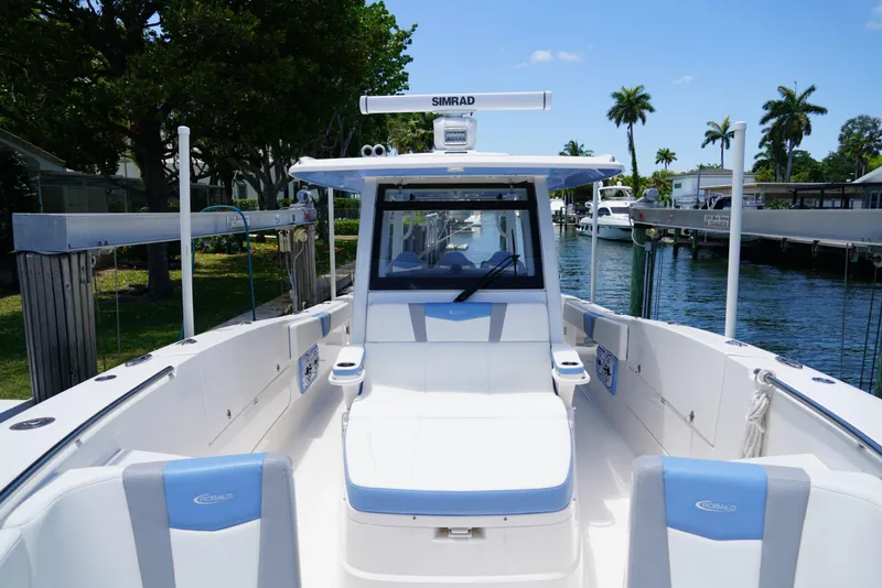Slide: The Image of 2024 Robalo R360 boat docked by a scenic waterfront with palm trees. - 18