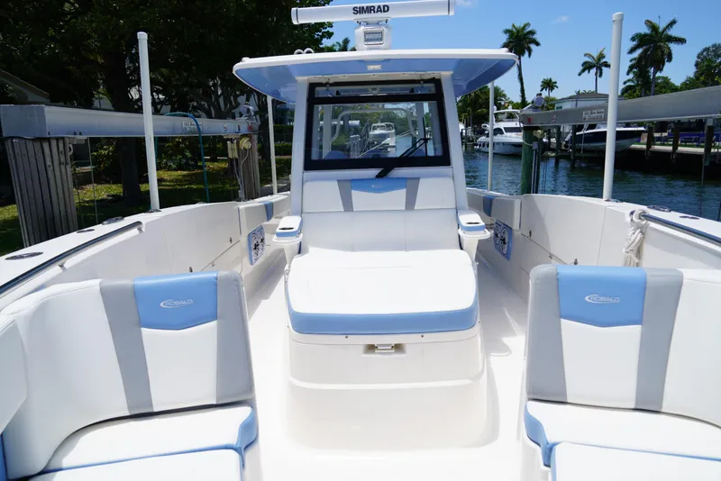 Slide: The Image of 2024 Robalo R360 boat interior with blue and white seating, docked near palm trees. - 19
