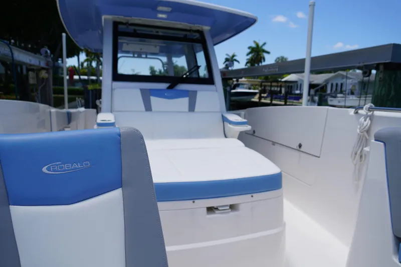 Slide: The Image of 2024 Robalo R360 boat interior with blue and white seating, docked under clear sky. - 20