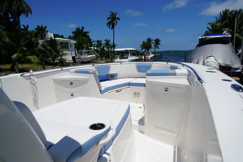 Slide: The Image of 2024 Robalo R360 boat interior with seating, docked near palm trees and water. - 25