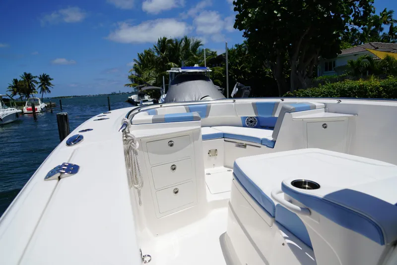 Slide: The Image of 2024 Robalo R360 boat interior with white and blue seating, docked by palm trees. - 26