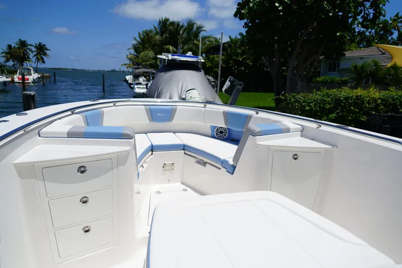 Slide: The Image of 2024 Robalo R360 boat interior with seating and storage, docked by a scenic waterfront. - 27