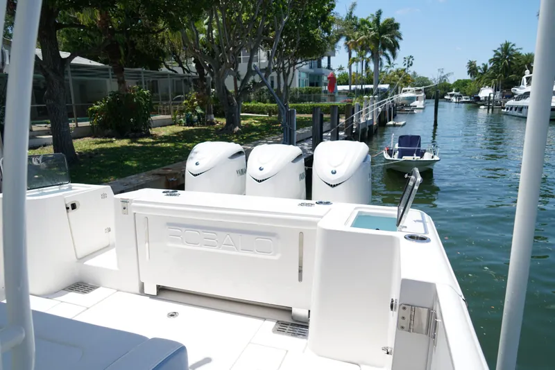 Slide: The Image of 2024 Robalo R360 boat docked with triple Yamaha engines, surrounded by lush greenery. - 39