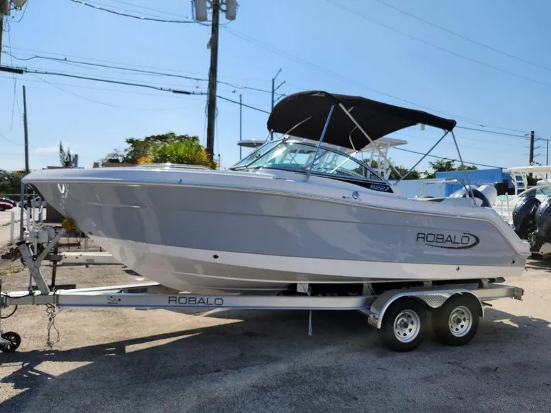 Slide: The Image of 2023 Robalo R227 boat on trailer, parked outdoors under clear sky. - 3