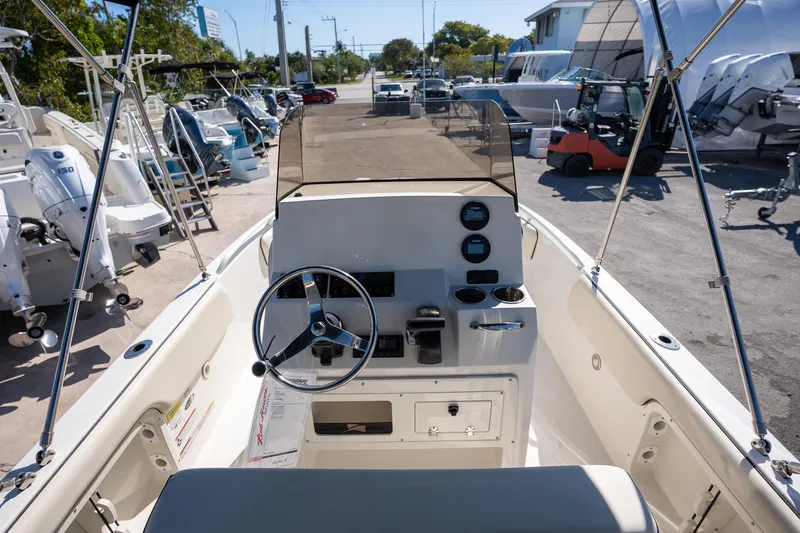 Slide: The Image of 2023 Stingray 173CC boat interior with steering wheel and control panel at a marina. - 9