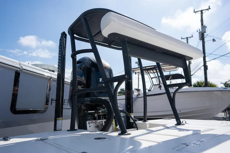 Slide: The Image of 2025 Hewes Redfisher 18 boat, rear view with motor and seating, under clear blue sky. - 6