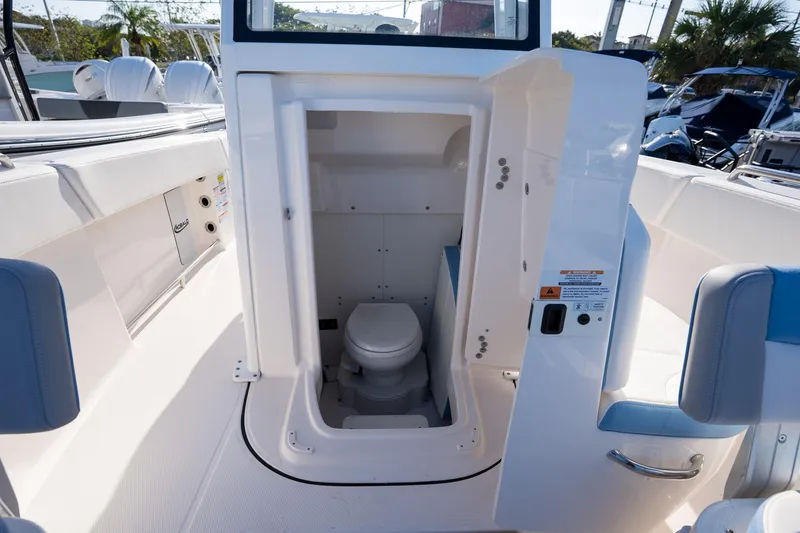 Slide: The Image of 2025 Robalo R250 boat interior with a compact marine toilet. - 14