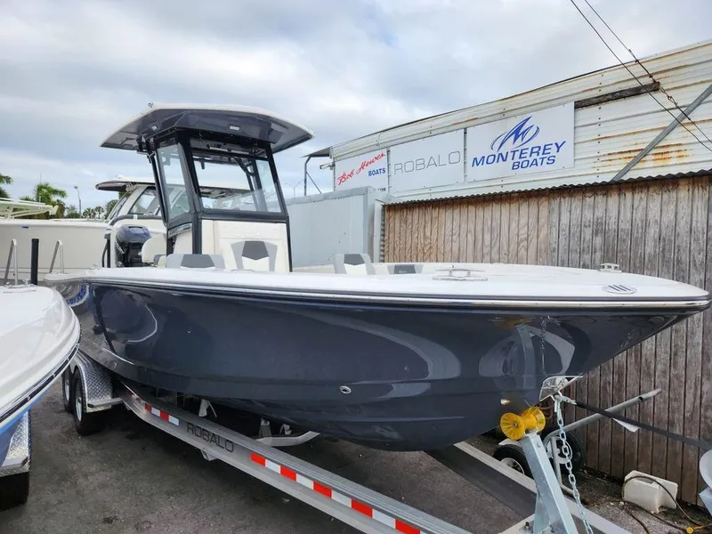 Slide: The Image of 2023 Robalo 266 Cayman boat on trailer, parked near Monterey Boats signage. - 13