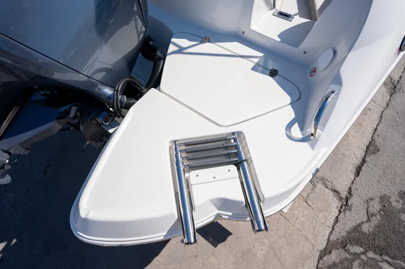 Slide: The Image of 2024 Stingray 211DC boat with stainless steel swim ladder and outboard motor. - 16