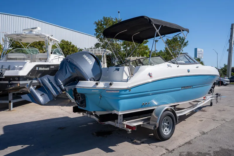 Slide: The Image of 2024 Stingray 211DC boat with Yamaha engine on trailer, parked outdoors. - 19