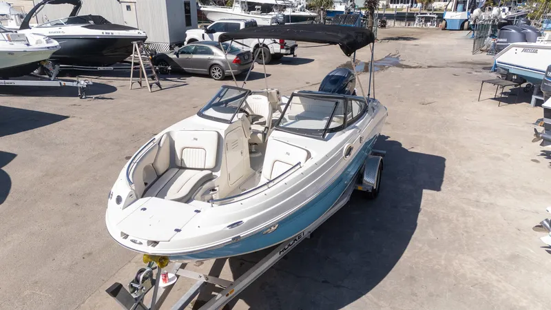 Slide: The Image of 2024 Stingray 211DC boat on trailer in marina setting. - 21