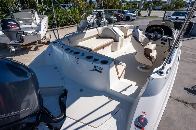 Slide: The Image of 2024 Stingray 192SC boat interior with seating and steering wheel, parked outdoors. - 10