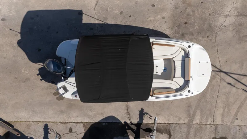 Slide: The Image of Overhead view of 2024 Stingray 192SC boat with black canopy on concrete surface. - 14
