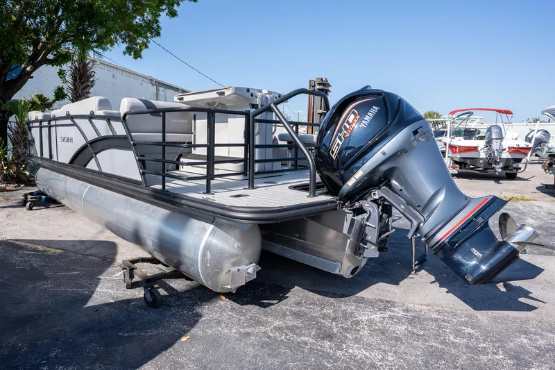 Slide: The Image of 2024 Sylvan L3 DLZ Bar pontoon boat with Yamaha outboard motor, parked outdoors. - 4
