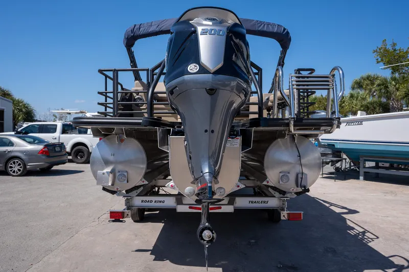 Slide: The Image of 2024 Sylvan L3 DLZ Bar pontoon boat with powerful outboard motor, parked on trailer. - 7