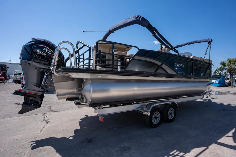 Slide: The Image of 2024 Sylvan L3 DLZ Bar pontoon boat on trailer, featuring a powerful outboard motor. - 8