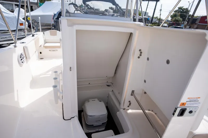 Slide: The Image of 2024 Robalo R180 boat interior with storage compartment and portable toilet. - 12