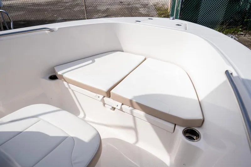Slide: The Image of 2024 Robalo R180 boat interior seating with white cushions and cup holders. - 13