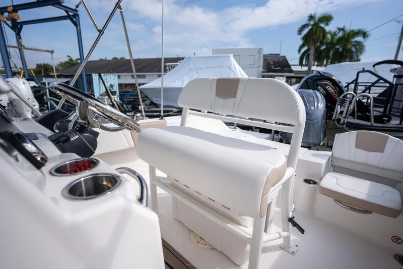 Slide: The Image of 2024 Robalo R180 boat interior with steering wheel and seating, docked under a clear sky. - 6