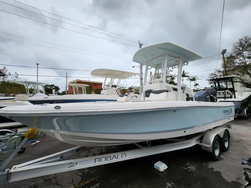 Slide: The Image of 2023 Robalo 226 Cayman boat on trailer, displayed outdoors under cloudy sky. - 1