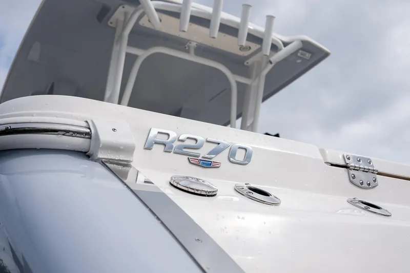 Slide: The Image of 2025 Robalo R270 boat, close-up of model name and sleek design under cloudy sky. - 7