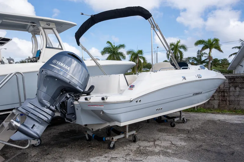 Slide: The Image of 2024 Stingray 212SC boat with Yamaha outboard motor, parked outdoors. - 11