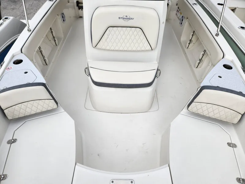 Slide: The Image of 2023 Stingray 206cc boat interior with white cushioned seating and storage compartments. - 13