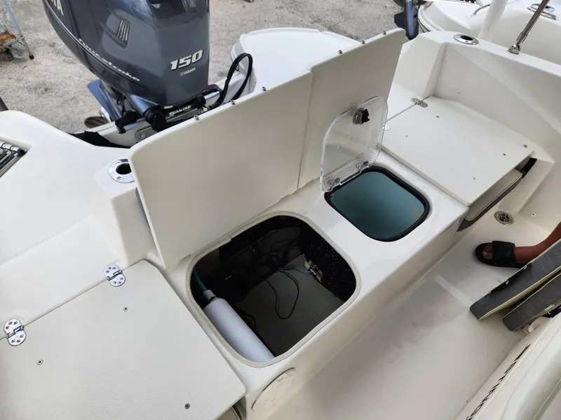 Slide: The Image of 2023 Stingray 206cc boat interior with open storage compartments and Yamaha 150 outboard motor. - 28