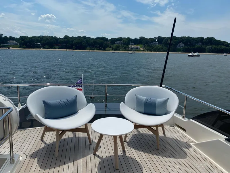 Slide: The Image of Ferretti Yachts 670, 2020 model, deck with chairs and table overlooking serene water. - 8