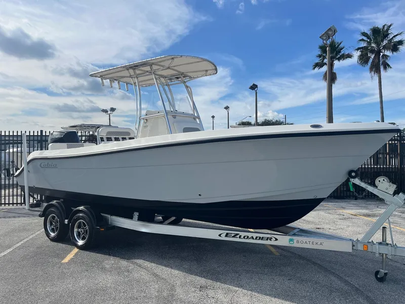 Slide: The Image of 2022 Cobia 237 Center Console boat on trailer, parked outdoors under a cloudy sky. - 3