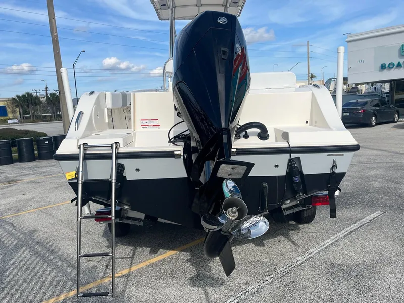 Slide: The Image of 2022 Cobia 237 Center Console boat with outboard motor and ladder, parked outdoors. - 4