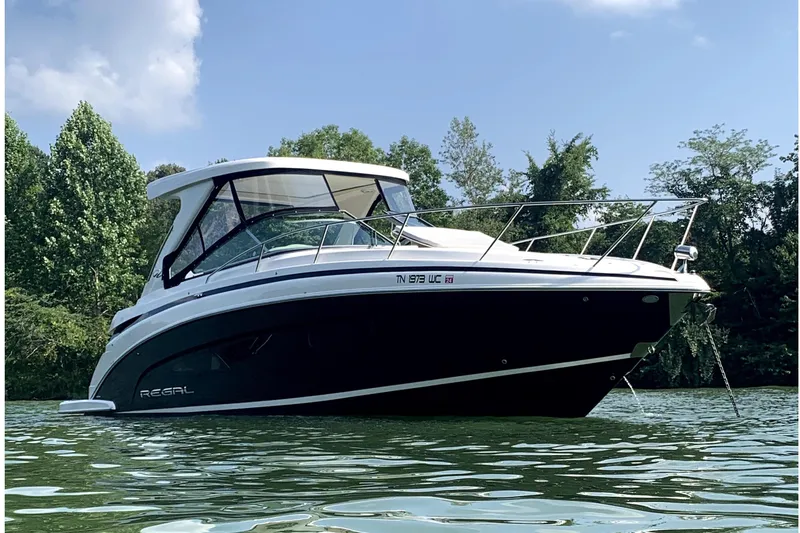 The Image of 2019 Regal 33 Express boat on calm water, surrounded by lush greenery. - 0
