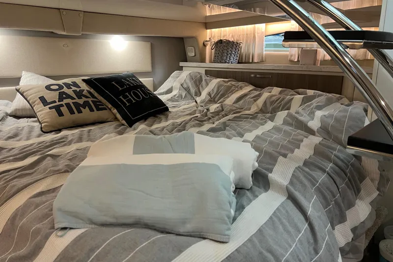 Slide: The Image of Cozy cabin interior of 2019 Regal 33 Express with striped bedding and decorative pillows. - 31